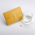 Envase de Vitamina C junto a un vaso de agua