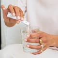 Mujer vertiendo un sobre de colágeno en un vaso