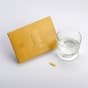 Envase de Vitamina C junto a un vaso de agua